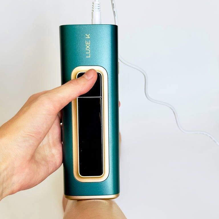 Hand holding a teal and gold electronic device with &